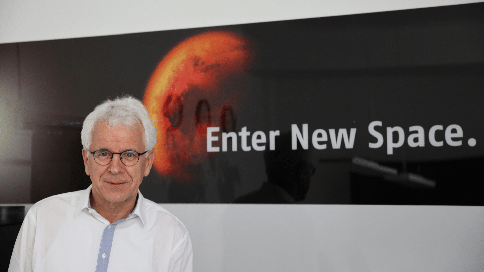 Portrait von Entwicklungsingenieur Karl-Heinz-Suphan vor einem Banner mit dem Slogan "Enter New Space." und dem Mars im Hintergrund