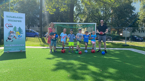 Dr. Baumgärtel and kindergarten children stand in front of the soccer goal donated by him